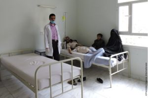 A doctor stands up in a room in hospital with someone sick from cholera