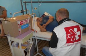 Valentina, dans son lit d'hôpital, reçoit la visite des équipes de Première Urgence Internationale