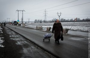 Une petite dame traverse un checkpoint à Mariinka
