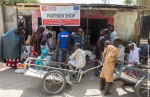 Personnes devant une boutique partenaire du projet innovant au Nigeria de Première Urgence Internationale